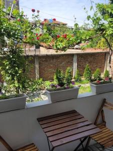 um banco de madeira sentado numa varanda com vasos de plantas em Plovdiv Top Center 2 Bdrm Apartment, 5min from Central Square & Garden, FREE Parking em Plovdiv
