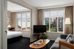 a hotel room with a bed and a tv and windows at Rydges Newcastle in Newcastle