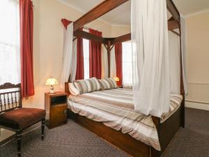 1 dormitorio con cama con dosel y silla en Beaufort House, en Ilfracombe