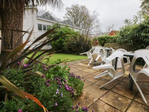 un grupo de sillas blancas y flores en un patio en Beaufort House, en Ilfracombe