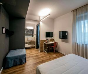 a room with a bed and a desk with a television at Best Western Hotel Corsi in Torrimpietra