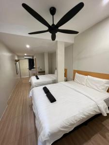 two beds in a room with a ceiling fan at Homestay Suria in Kuala Kangsar