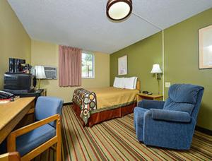 a hotel room with a bed and two chairs at Super 8 by Wyndham Minot Airport in Minot