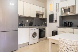 a kitchen with white cabinets and a washer and dryer at Apartment in front of the ocean in Los Cristianos
