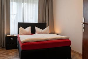Schlafzimmer mit einem Bett mit einem roten und schwarzen Kopfteil in der Unterkunft Hotel Ammerland garni in Wilhelmshaven