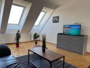 uma sala de estar com um sofá e uma televisão numa cómoda em Dachgeschoss für 4 mit Terrasse em Viena