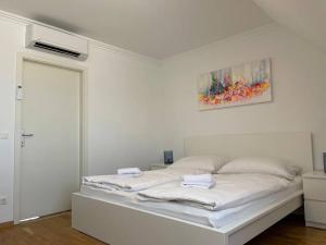 a white bedroom with a bed with two towels on it at Dachgeschoss für 4 mit Terrasse in Vienna