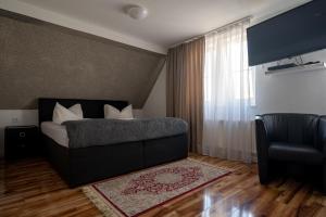 a bedroom with a bed and a chair and a window at Hotel Ammerland garni in Wilhelmshaven