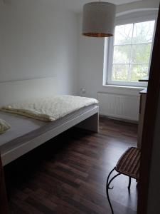 ein Schlafzimmer mit einem Bett, einem Fenster und einem Stuhl in der Unterkunft LANDHAUS LAAVE FERIENWOHNUNG 