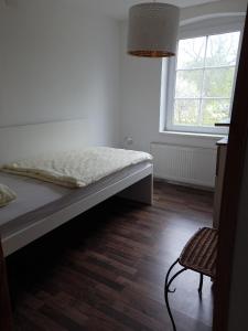 a bedroom with a bed and a window and a chair at LANDHAUS LAAVE FERIENWOHNUNG in Laave