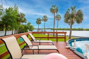 una terraza con sillas, una piscina y palmeras en Stunning Tampa Bay Waterfront House with Pool en Riverview