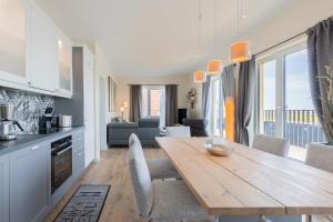 a kitchen and dining room with a wooden table at Penthouse SeeZeichen mit Seeblick in Nordstrand