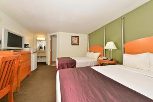 a hotel room with two beds and a flat screen tv at Charleston Eagle Inn in Charleston