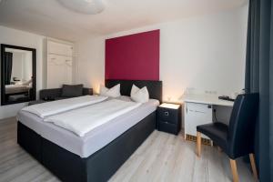 a bedroom with a bed and a desk and a chair at Hotel Ammerland garni in Wilhelmshaven
