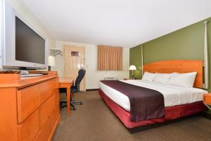 Habitación de hotel con cama y escritorio con TV. en Charleston Eagle Inn, en Charleston