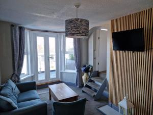 ein Wohnzimmer mit einem blauen Sofa und einem TV in der Unterkunft The Trelinda Guest House in Newquay