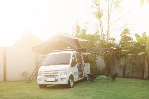 a white van parked in a yard with a tent at Campervan Bali Rental in Dalung