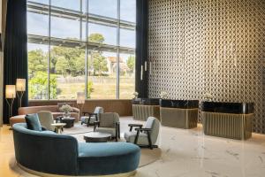 a lobby with couches chairs and tables and windows at Renaissance Porto Lapa Hotel in Porto