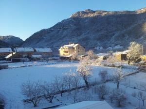 una casa está cubierta de nieve frente a una montaña en Hotel Cotiella, en Campo