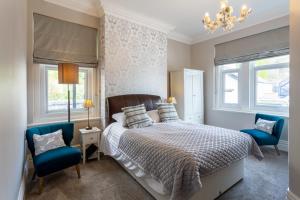 a bedroom with a bed and two blue chairs at Sefton Court in Llandudno