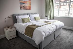 a bedroom with a large bed with white sheets and green pillows at Wave Stays - Ground Floor Apartment in Cleveleys