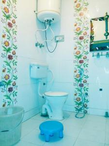 a bathroom with a toilet and a blue stool at Hotel Fabulous Kashmir in Srinagar