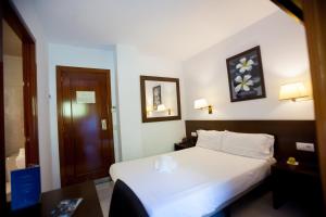 Habitación de hotel con cama blanca y puerta de madera en Insitu Eurotel Andorra en Andorra la Vella