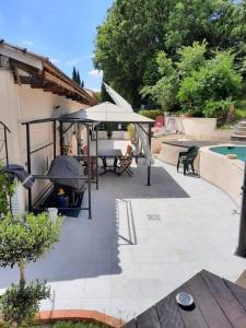 - une terrasse avec une table et un parasol à côté de la piscine dans l'établissement BORA BORA Maison les palmiers., à Venelles
