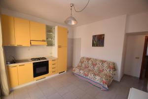 a kitchen with yellow cabinets and a couch in a room at Bilocale SABBIA 3 - Zona mare con terrazza, clima e posta auto in Marina di Campo +14 photos