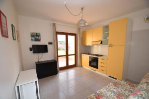 a room with a kitchen with yellow cabinets and a table at Bilocale SABBIA 3 - Zona mare con terrazza, clima e posta auto in Marina di Campo