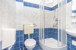 a blue tiled bathroom with a toilet and a sink at Hotel Villa Aurora in Crikvenica