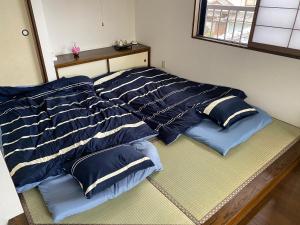 Una cama con almohadas azules y blancas. en ゲストハウス宮崎 guesthouse miyazaki バックパッカー向け個室旅人宿 P有, en Miyazaki