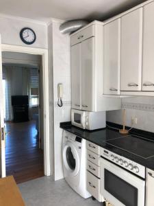 a kitchen with white cabinets and a washer and dryer at Dúplex con vistas a la ría de Mogro by Alterhome in Mogro