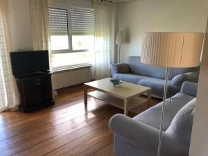 ein Wohnzimmer mit einem Sofa, einem TV und einem Tisch in der Unterkunft Dúplex con vistas a la ría de Mogro by Alterhome in Mogro