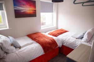 two beds in a room with two windows at Wave Stays - First Floor Apartment in Cleveleys