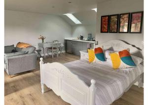 Una cama blanca con almohadas coloridas en un dormitorio en Acorn Attic, a modern, new first floor garden annex, en Great Ouseburn