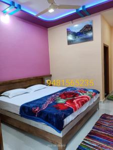 a bedroom with a bed with a purple wall at Abhi Homestay Hampi in Hampi