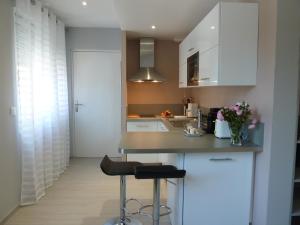 una cocina con armarios blancos, encimera y taburete en Studios Albri, en Nogent-sur-Marne