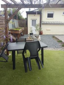 uma mesa preta e uma cadeira num jardim com um banco em Le Paradis em Fressies
