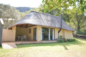a small house with a thatched roof at Rocky Drift Private Nature Reserve in Waterval Boven