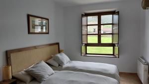 1 dormitorio con 2 camas y ventana en Preciosa Casa de Indiano En Noriega (Asturias) en Noriega