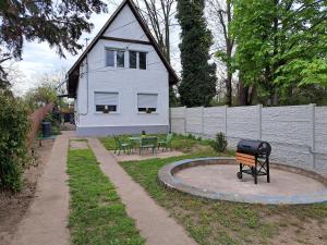 a white house with a grill in a yard at Sünfészek Vendégház in Göd