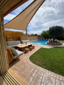 une terrasse avec un canapé, une table et une piscine dans l'établissement Villa Olivetti, à Anavyssos