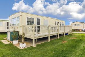 a mobile home with a deck on a lawn at 8 Berth Caravan For Hire By The Beautiful Beach In Heacham, Norfolk Ref 21055a in Heacham