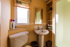a bathroom with a toilet and a sink and a window at 8 Berth Caravan For Hire By The Beautiful Beach In Heacham, Norfolk Ref 21055a in Heacham