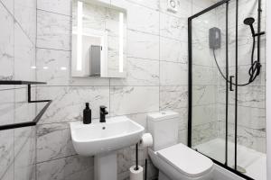 a white bathroom with a sink and a toilet at Luxurious Duplex in Bolton – Sleeps 6 – Parking in Bolton