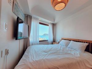 ein Schlafzimmer mit einem Bett und einem großen Fenster in der Unterkunft Seogwiporto in Seogwipo