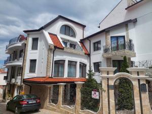 a white house with a car parked in front of it at Family Hotel Rai in Shumen