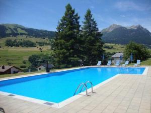 a large blue swimming pool with mountains in the background at Tgesa Sunnmatt Nr 46 in Savognin
