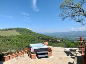 a hot tub on a patio with a view of the mountains at Agriturismo Il Colle in Poggio Alla Croce